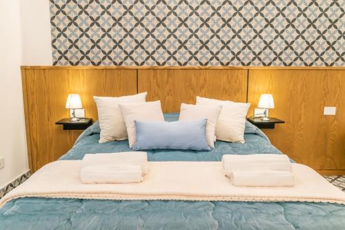 a bedroom with a blue bed with two lamps at Community Rooms & Wine in Favara