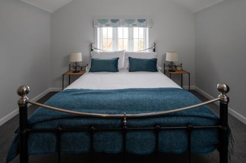 a bedroom with a large bed with a blue blanket at Gamekeeper's Cottage in Dorchester