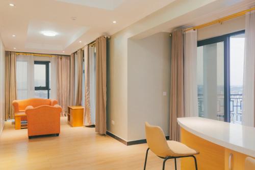 a living room with a table and chairs and windows at Tropical Plaza Apartments in Kigali
