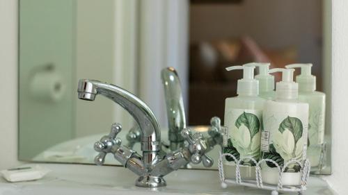 a sink with two bottles of soap and a mirror at Eastcliff Cottage in Hermanus