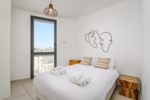 ein Schlafzimmer mit einem weißen Bett mit zwei Gesichtern an der Wand in der Unterkunft Spacious 3 BDR in Florentine in Tel Aviv