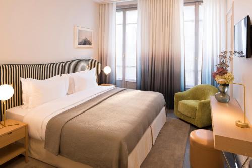 Pokój hotelowy z łóżkiem i krzesłem w obiekcie Hôtel Le Marianne w Paryżu
