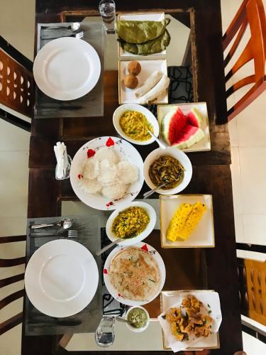 a table with plates and bowls of food on it at Gold Crown Residence in Dambulla