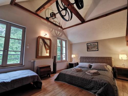 a bedroom with a bed and a mirror and windows at Le Petit Moulin in Faverelles