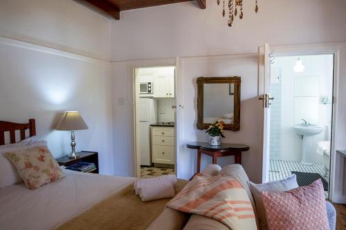 a bedroom with a bed and a mirror and a sink at Eastcliff Cottage in Hermanus
