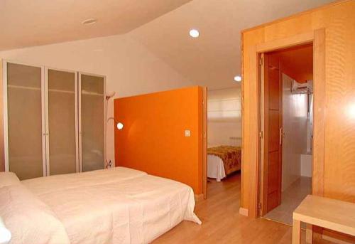 ein Schlafzimmer mit einem großen Bett und einer orangefarbenen Wand in der Unterkunft Apartamentos Turísticos Silvano Posada de Llanes in Posada de Llanes