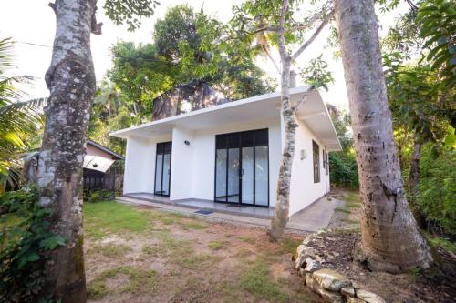 una casa blanca con árboles delante de ella en Chef Naturelle's Guest House, en Kandy