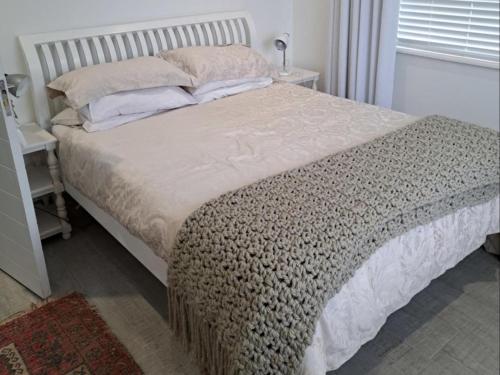 a large bed in a bedroom with a window at Barefoot Bungalow in Yzerfontein