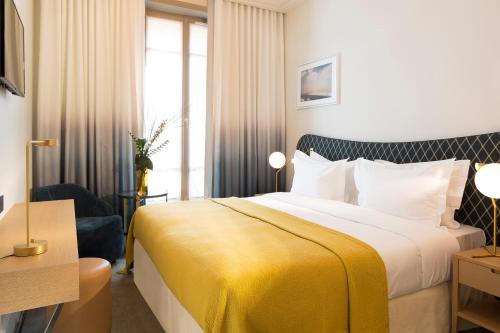 a hotel room with a bed with a yellow blanket at Hôtel Le Marianne in Paris