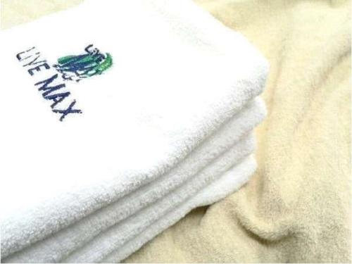 una pila de toallas blancas sentadas en una cama en HOTEL LiVEMAX Kitafuchu, en Fuchu