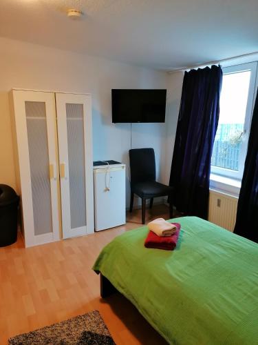 a bedroom with a green bed and a chair and a window at Löwen Unterkunft Braunschweig in Braunschweig