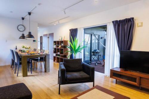 a living room with a table and a dining room at テラスでBBQ&サウナ&ジャグジー付き 築浅おしゃれな貸別荘 最大16名宿泊可能 Cottage Uruma in Uruma
