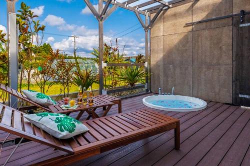 a wooden deck with a hot tub and a bench at テラスでBBQ&サウナ&ジャグジー付き 築浅おしゃれな貸別荘 最大16名宿泊可能 Cottage Uruma in Uruma