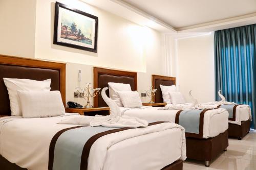 un grupo de 4 camas en una habitación de hotel en Al Raad Hotel, en Áqaba