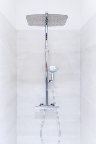 d'un pommeau de douche dans une salle de bains aux murs blancs. dans l'établissement Le Crêt - Place Jean Jaurès, à Saint-Étienne