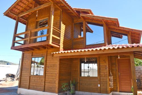 ItapemirimにあるMillicent Residence - Chalet Milly e Chalet Iris - Itaoca Praia - ESの木造の家屋で、バルコニーが付いています。