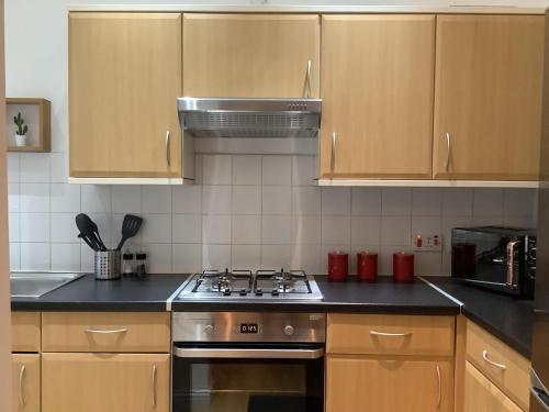 a kitchen with wooden cabinets and a stove top oven at Ground Floor Apartment with Garden in Glasgow