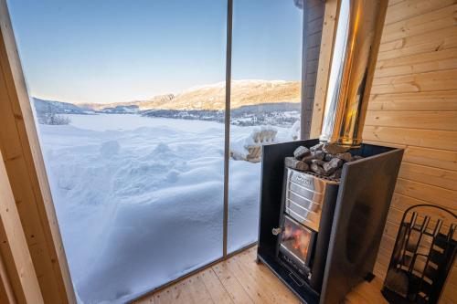 a fireplace in a room with a view of a lake at Stamp and sauna! Small farm with fantastic view! in Favang