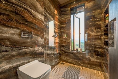 a bathroom with a toilet and a glass shower at SaffronStays HeavOne Trio, Lonavala in Lonavala