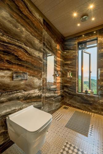 a bathroom with a toilet and a glass shower at SaffronStays HeavOne Trio, Lonavala in Lonavala