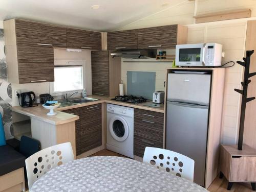 a small kitchen with a refrigerator and a microwave at Mobilhome 4/6 personnes proche La Palmyre, Royan in Saint-Augustin