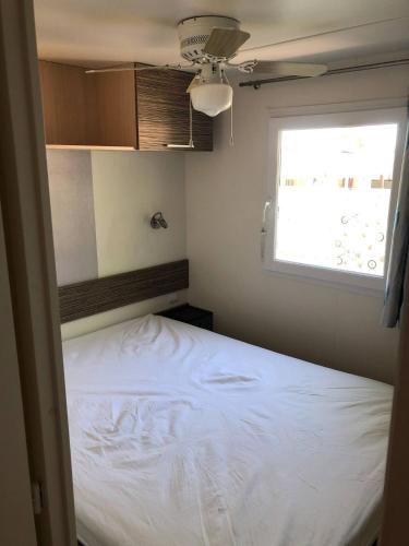 une petite chambre avec un lit blanc et une fenêtre dans l'établissement Mobilhome 4/6 personnes proche La Palmyre, Royan, à Saint-Augustin
