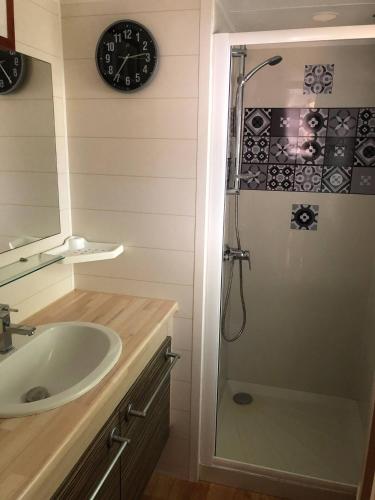 La salle de bains est pourvue d'un lavabo et d'une douche avec une horloge. dans l'établissement Mobilhome 4/6 personnes proche La Palmyre, Royan, à Saint-Augustin