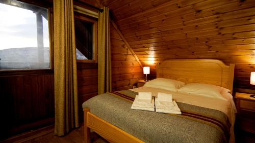 ein Schlafzimmer mit einem Bett in einem Blockhaus in der Unterkunft Chalé | Penhas da Saúde - Serra da Estrela in Penhas da Saúde