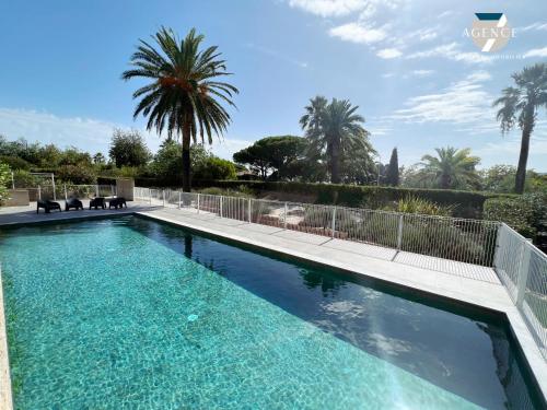 - une piscine dans une villa avec des palmiers dans l'établissement Appartement New Green, à Grimaud