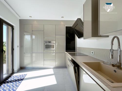kuchnia z białymi szafkami i zlewem w obiekcie Appartement New Green w mieście Grimaud