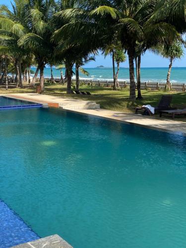 a large swimming pool with palm trees and the ocean at Luxury Penthouse, Nilaveli in Trincomalee