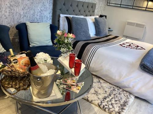 Adorable private couples retreat with hot tub في Llanfechell: غرفة نوم مع سرير وطاولة مع زجاجات النبيذ