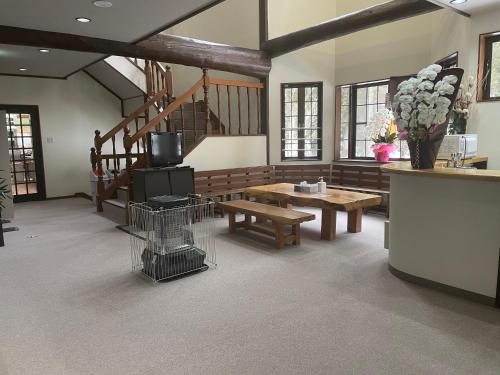 a living room with a table and benches and stairs at K・Lodge in Yuzawa