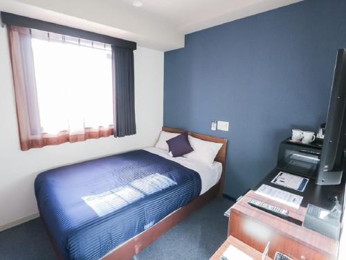 een kleine slaapkamer met een bed en een televisie bij HOTEL LiVEMAX Machida-Ekimae in Machida