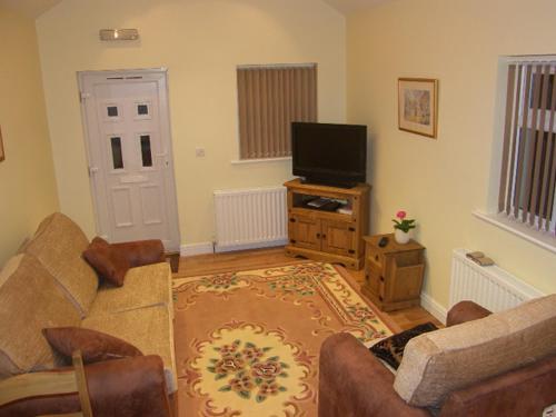 a living room with a couch and a television at Pinfold Holiday Cottage in Laxey