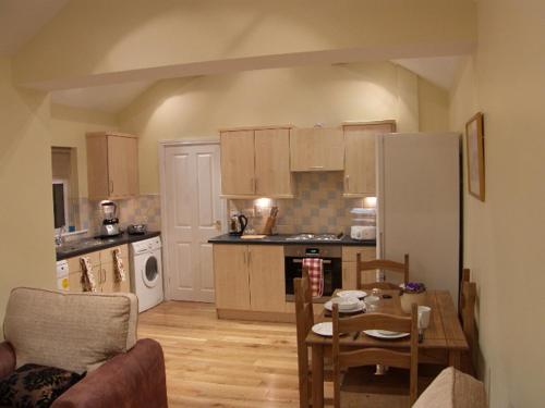 a kitchen with a table and a dining room at Pinfold Holiday Cottage in Laxey