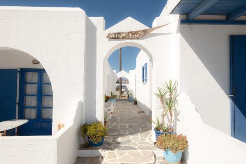 a walkway through a white building with potted plants at Christina's House in Koufonisia