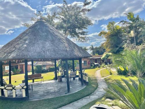 a gazebo with a bench and a grass roof at REED MAT LODGE in Lusaka