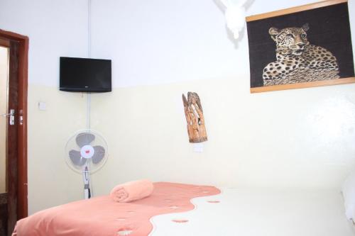 ein Schlafzimmer mit einem Bett und einem Ventilator sowie einem Bild eines Leoparden in der Unterkunft REED MAT LODGE in Lusaka