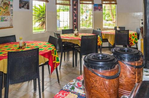 un comedor con mesas, sillas y ventanas en REED MAT LODGE en Lusaka