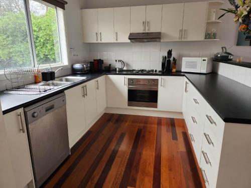 a kitchen with white cabinets and a wooden floor at Rye Getaway on Loatta in Rye