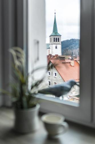 a window with a view of a church with a tower at Apartament ZajkoSki in Duszniki Zdrój