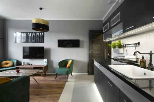 a kitchen with a sink and a living room at Apartament ZajkoSki in Duszniki Zdrój