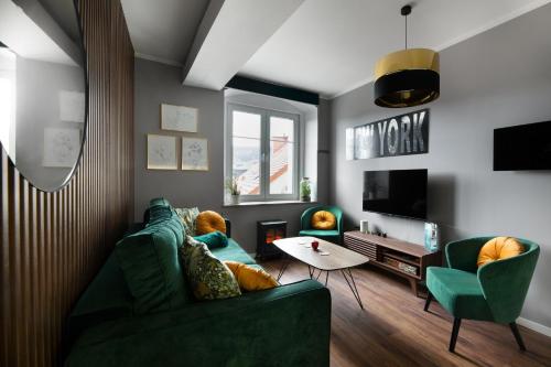 a living room with a green couch and chairs at Apartament ZajkoSki in Duszniki Zdrój