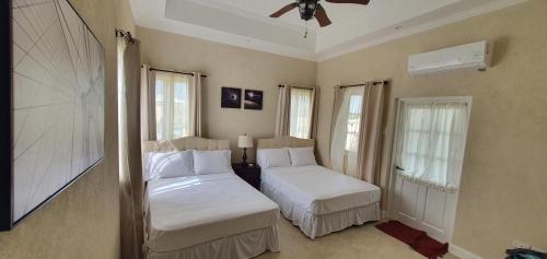 a bedroom with two beds and two windows at Infinity Townhomes at Bagatelle in Saint James