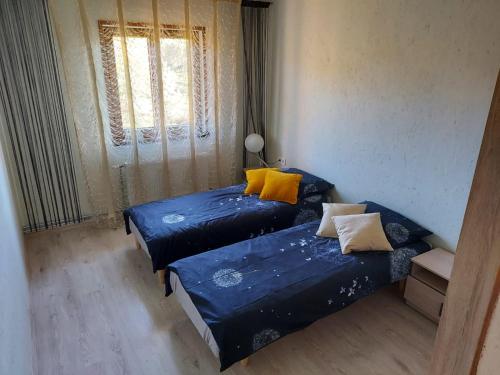 two beds in a room with blue sheets and yellow pillows at Atpūtas komplekss Burtakas in Straupe