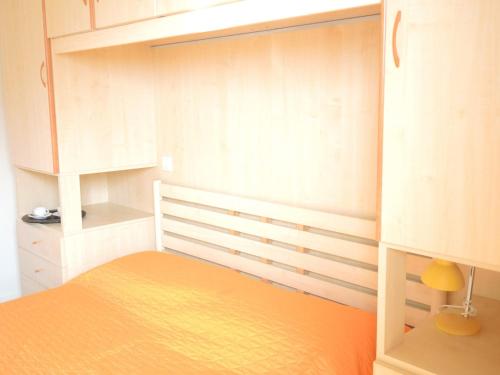 Schlafzimmer mit einem orangefarbenen Bett und weißen Schränken in der Unterkunft Nice flat for six guests by the sea - Beahost in Bibione
