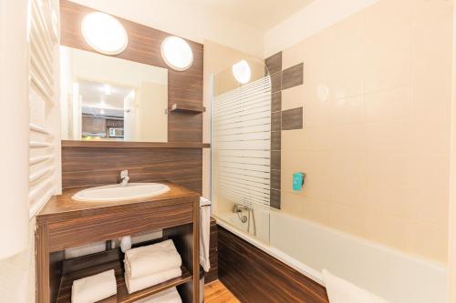 a bathroom with a sink and a mirror and a tub at Appart'City Classic Genève - Gaillard in Gaillard