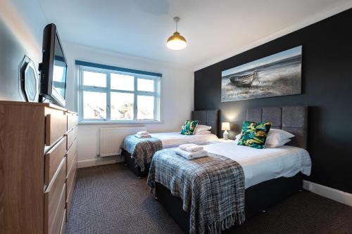 1 dormitorio con 2 camas y TV de pantalla plana en Comfortable and convenient stay 3 bed house, en Southampton