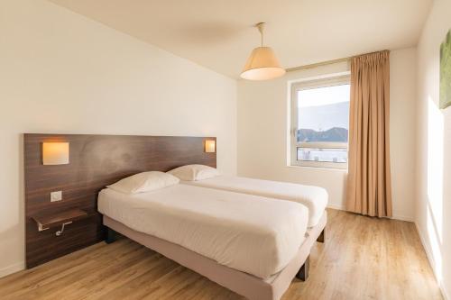 ein Hotelzimmer mit einem Bett und einem Fenster in der Unterkunft Appart'City Classic Genève - Gaillard in Gaillard